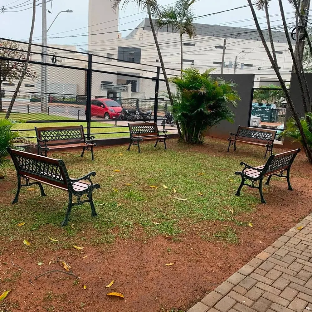 Bancos de jardín diseño cuadrillé, con respaldo calado y listones de madera, sobre el césped de un jardín