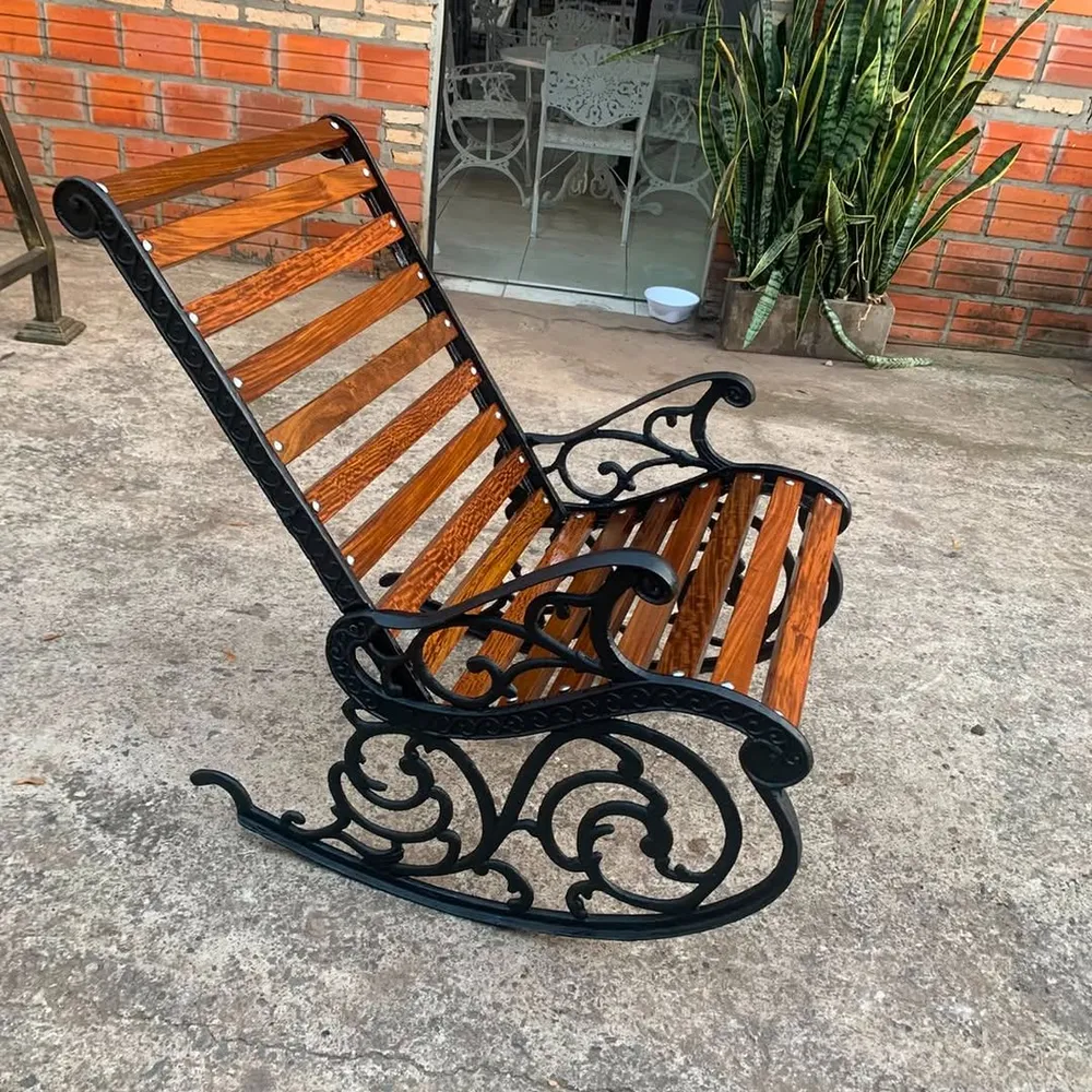Mecedora de aluminio fundido negro con listones de lapacho lustrado, contra una pared de ladrillo
