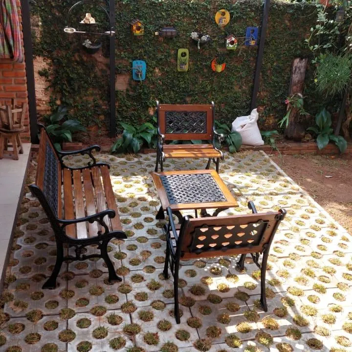 Juego de jardín diseño mimbre en un patio: banco, sillón y mesa con tapa calada, en hierro negro y madera