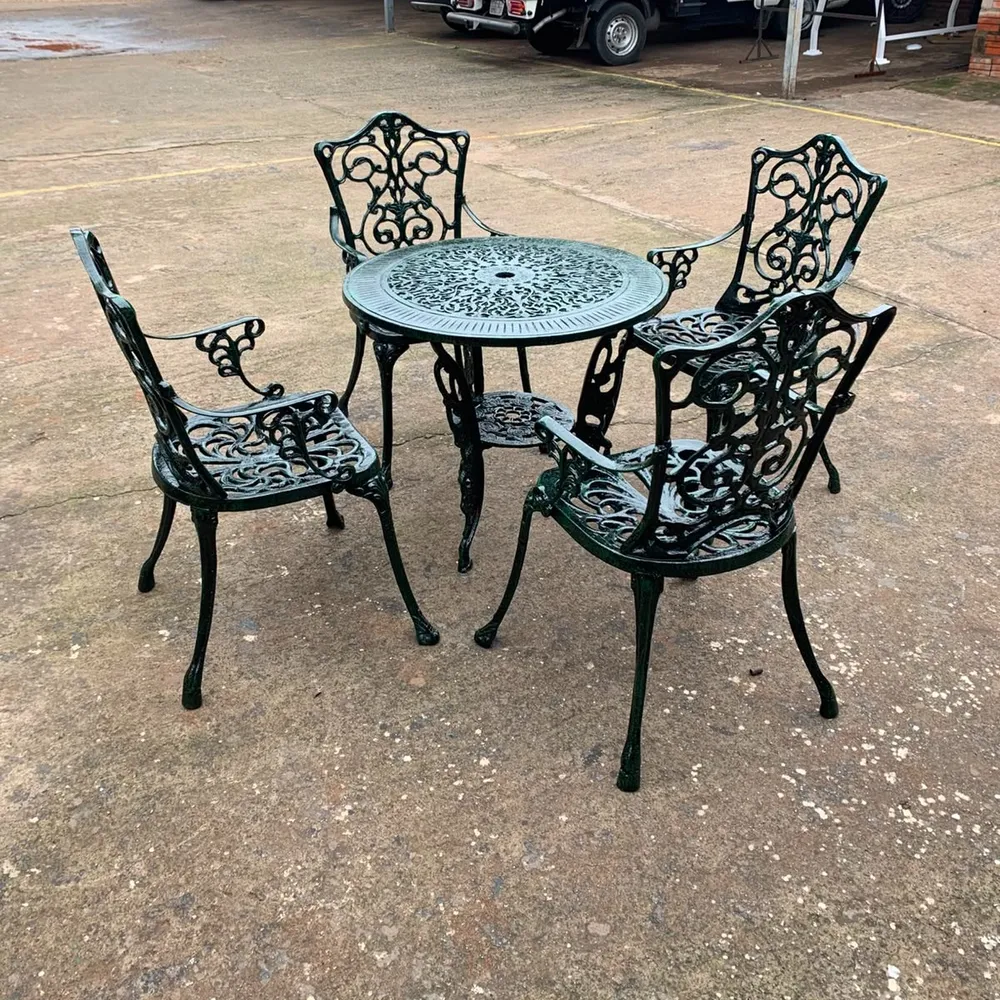 Mesa redonda calada con cuatro sillas de aluminio fundido en verde oscuro